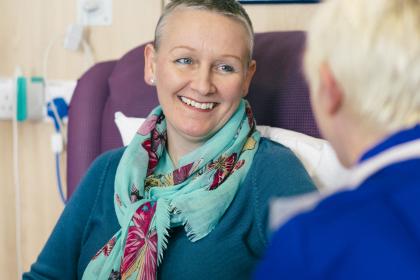 A woman smiles at a nurse while having chemotherapy