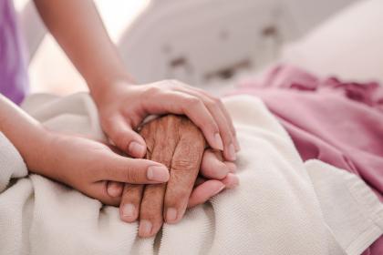 Two people holding hands on a hospital bed