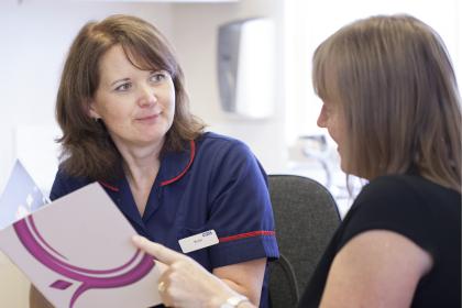 A nurse talking through a Target Ovarian Cancer leaflet with a woman
