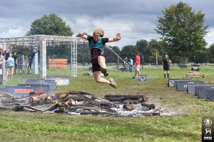 Georgia jumping over a ditch taking on the spartan challenge in her target ovarian cancer tshirt