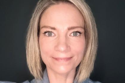 A close up headshot image of Catherine smiling wearing a blue shirt