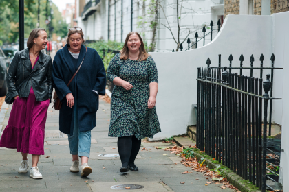 Three women walking down the street together all chatting a smiling