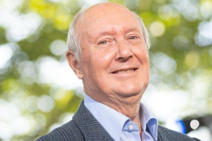 A photo of Sir Kenneth Calman smiling wearing a suit and shirt