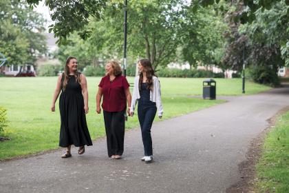 Three women walking together in the park chatting and smiling