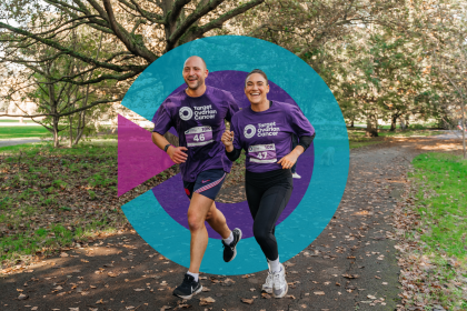 Two people running through a park with the Target Ovarian Cancer logo behind them