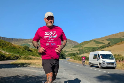Adam smiles as he runs during his seven ultramarathon challenge in August 2026.
