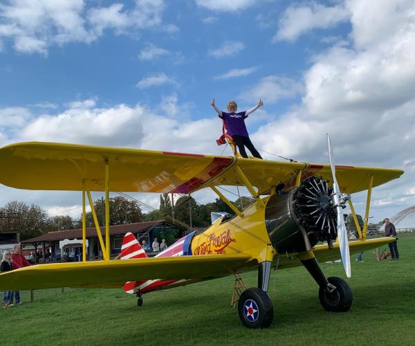 A female supporting on the top of a plane doing a wingwalking challenge