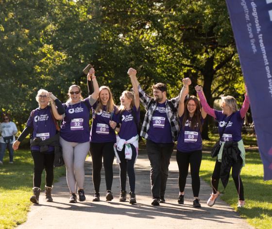 A group of fundraisers in Target Ovarian Cancer t-shirts, walking with their arms in the air