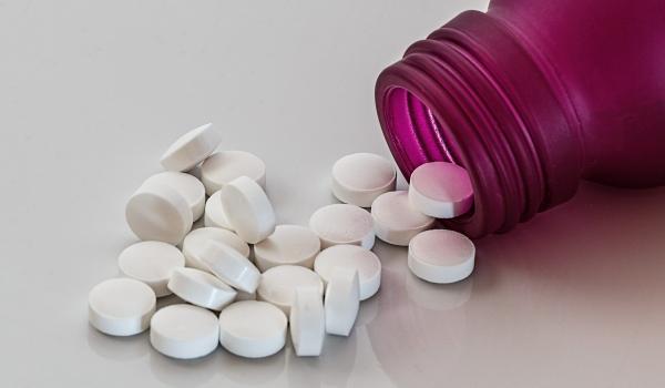 Purple bottle with white pills spilling out of it