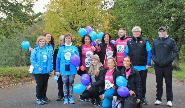 A group of fundraisers at the Ovarian Cancer Walk|Run holding balloons and smiling at the camera.JPG