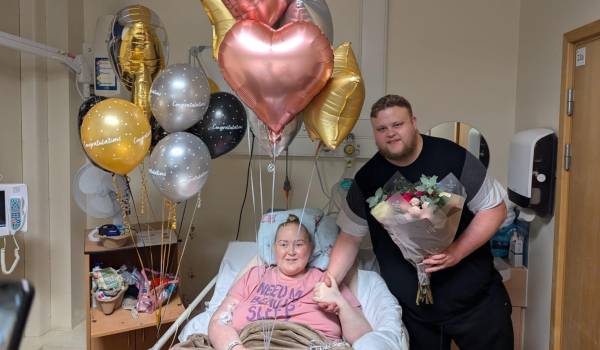 Edd and his wife Sophie smiling after Edd proposed, surrounded by balloons in hospital.
