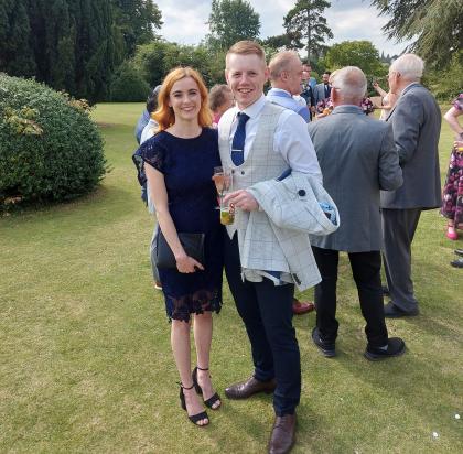 Lucy and her partner John pictured at a wedding in September 2023 wearing a dress and suit