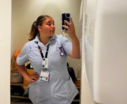 Rosie taking a photo in the mirror wearing her student nurse uniform