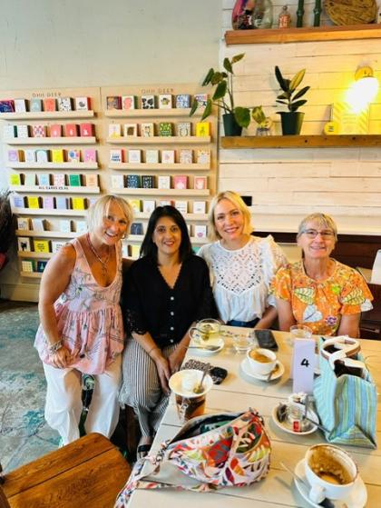 A photo of three women sitting in a cafe all smiling whilst attending a support group to meet other women with an ovarian cancer diagnosis