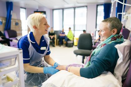 A nurse talking and smiling with a woman during chemotherapy