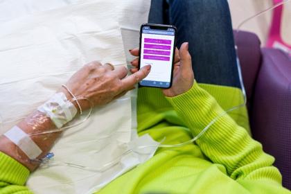 Close up of a woman scrolling through Target Ovarian Cancer's website on her phone during chemotherapy