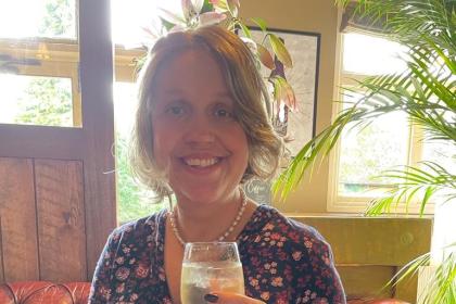 Alex wearing a dress and holding a glass of wine