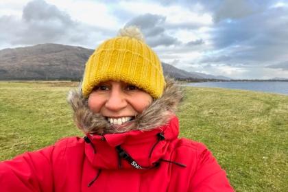 Allyson taking a selfie on a walk by the sea in a winter hat and coat smiling to the camera