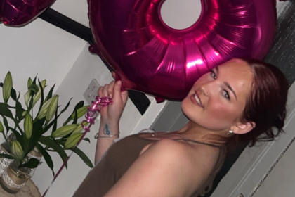 A photo of Taegan on her 18th birthday holding pink 1 and 8 balloons