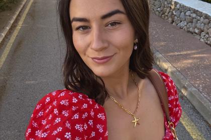A selfie of Lucy wearing a red dress with short brown hair smiling