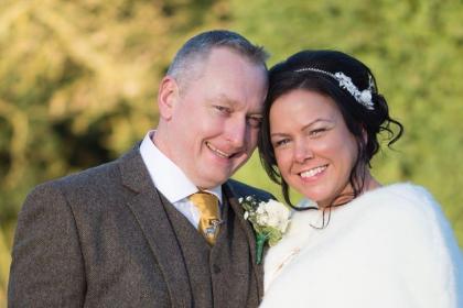 Carl and Fiona on their wedding day, with their heads close together smiling