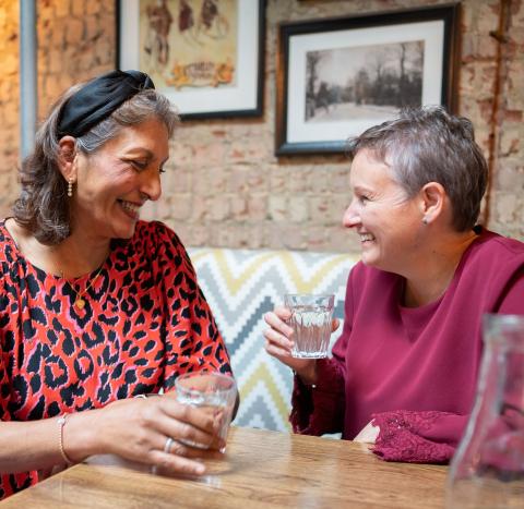Two women laughing and talking in a restaurant