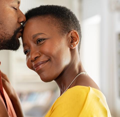 Woman smiling and man kissing her forehead