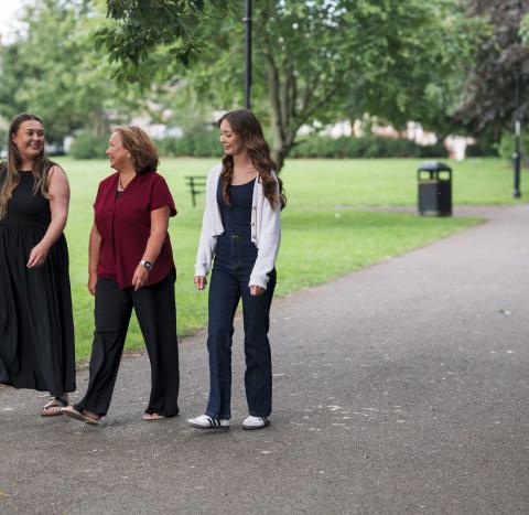Woman and her two adult daughters walking in a park