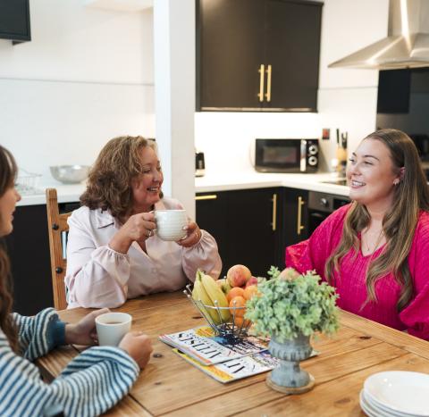Three women sat round a dining room table