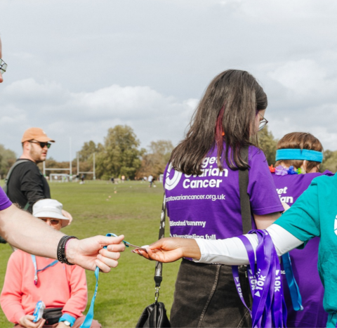 A woman handing a medal to an Ovardressed participant