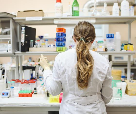 A female researcher facing away from the camera using equipment in a lab