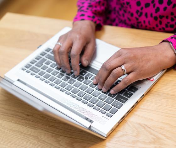 A person's hands typing on a laptop