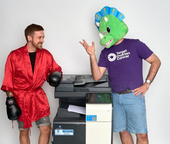 Two people in fancy dress costumes by an office printer