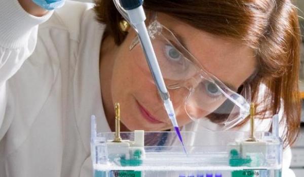 Close-up of a researcher wearing protective goggles while using equipment in a lab