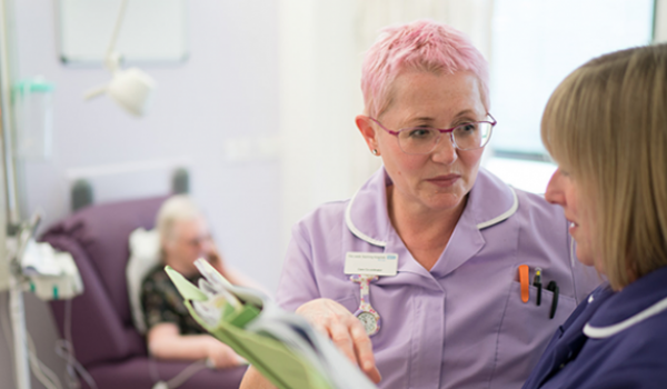 Two nurses discuss patient notes in a chemotherapy unit