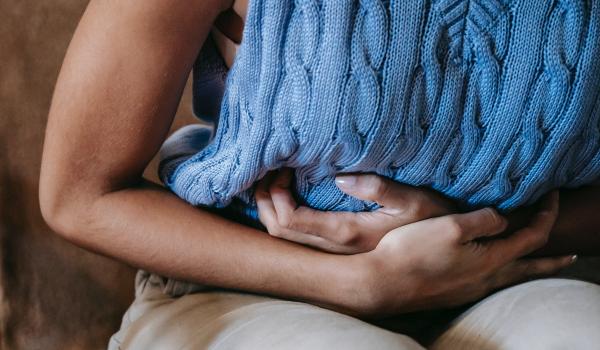 Close up of a woman with her hands on her bloated tummy