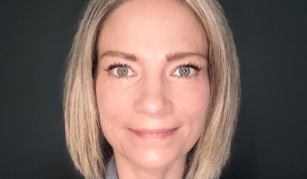 A close up headshot image of Catherine smiling wearing a blue shirt