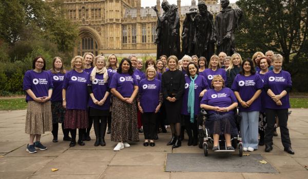 A group of Target Ovarian Cancer campaigners standing outside parliament wearing purple TOC tshirts with new CEO Catherine standing in the middle