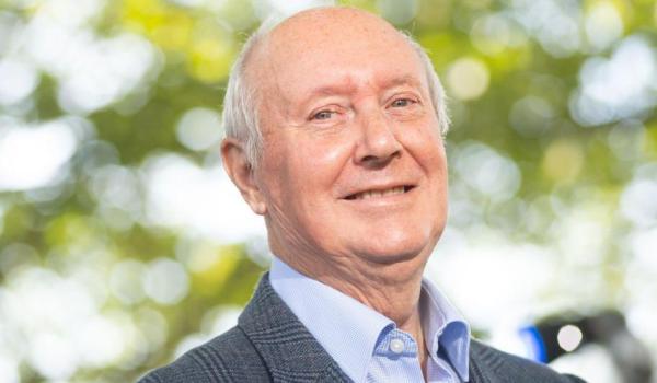 A photo of Sir Kenneth Calman smiling wearing a suit and shirt