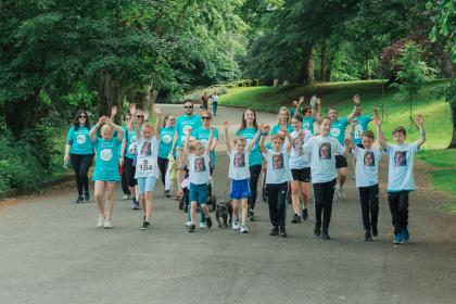 A large group of fundraisers holding their arms in the air as they take part in the Ovarian Cancer Walk|Run