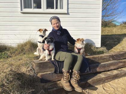 Anne sitting on a wall surrounded by three small dogs