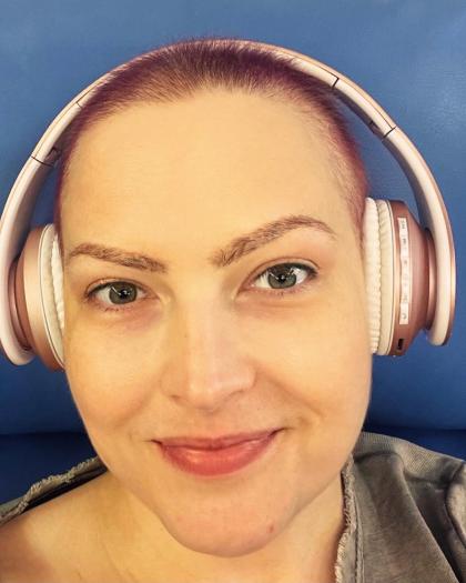 Kate after chemo, smiling and wearing headphones