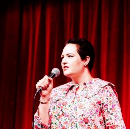 Kate on stage holding a microphone doing her first stand-up comedy gig