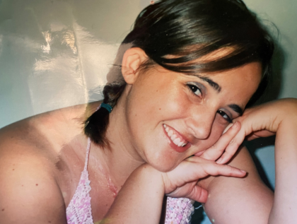 A photo of Leanne with her face resting against her hands and smiling