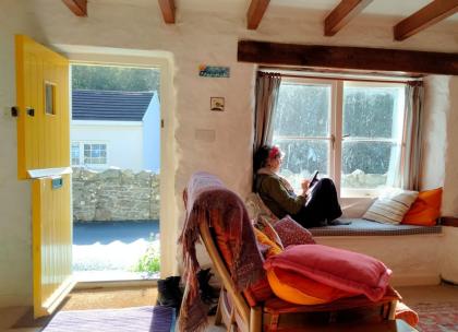 Hilary sat in a window seat in a cottage room looking out of the window