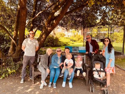 Sue pictured with her family and grandchildren all together on a park bench