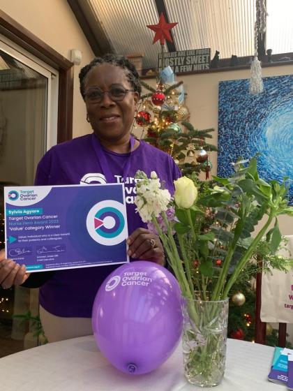 A photo of Sylvia Agyare with her Nurse Hero Award certificate wearing a Target Ovarian Cancer tshirt