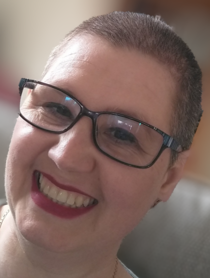 Jennifer wearing black glasses and red lipstick smiling at the camera