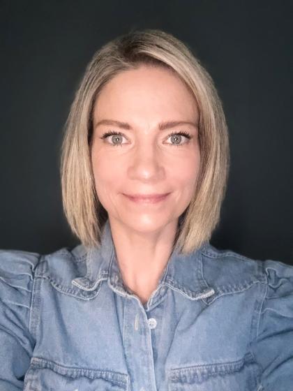 A close up headshot image of Catherine smiling wearing a blue shirt