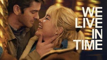 The poster for the film We Live in Time - it features a man and woman looking at each other closely and smiling